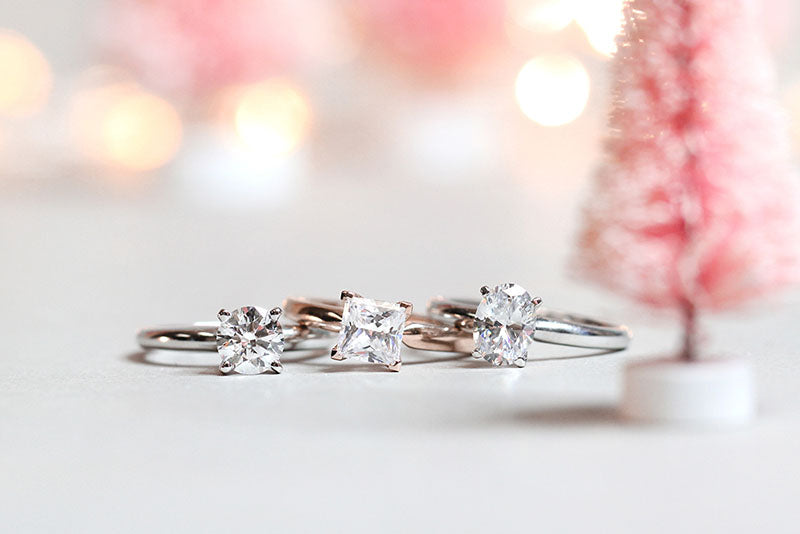Three affordable solitaire engagement rings containing  round cut princess cut and oval cut lab grown diamonds