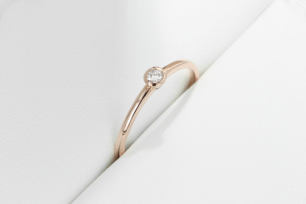 Simple and sleek stackable band with a small bezel set recycled diamond at the center